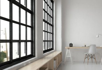 A minimalist room with large black frame picture windows and a study desk and chair